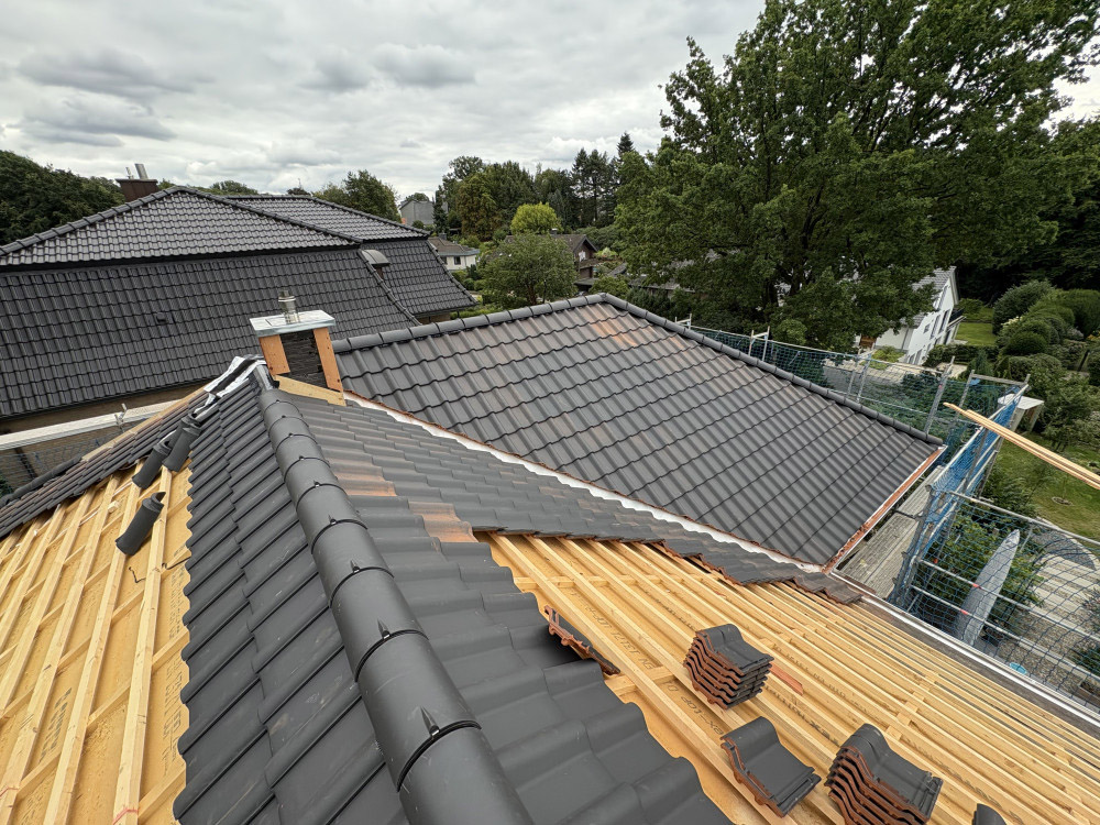 Neues Dach mit schwarzen Ziegeln in der Fertigstellung Bauarbeiten an einem Hausdach mit dunkler Dacheindeckung und sichtbarer Holzkonstruktion